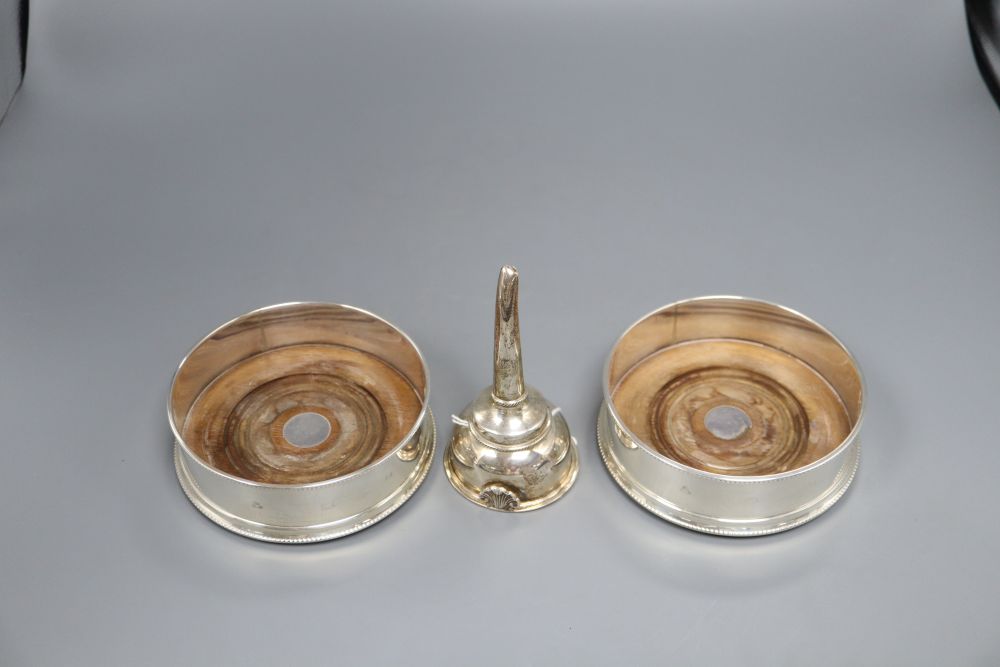 A pair of bottle coasters with beaded rims and turned hardwood bases, London 1991, width 14cm and a George III style wine funnel